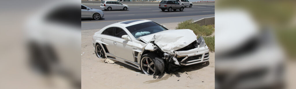 A white car that has been smashed in the road.